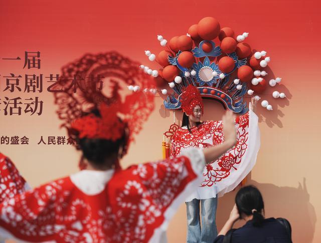 汉口江滩上,市民游客在中国京剧节展板前打卡拍照。 记者何晓刚摄