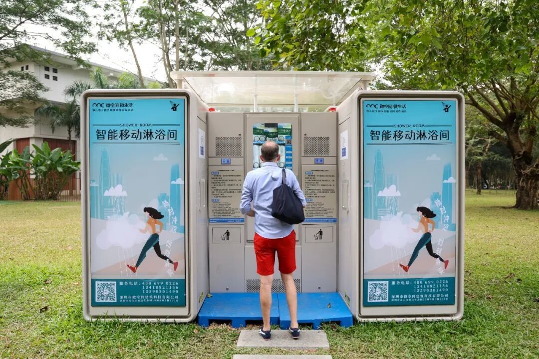 外国游客在深圳莲花山公园里了解智能移动淋浴间/新华社记者 梁旭 摄