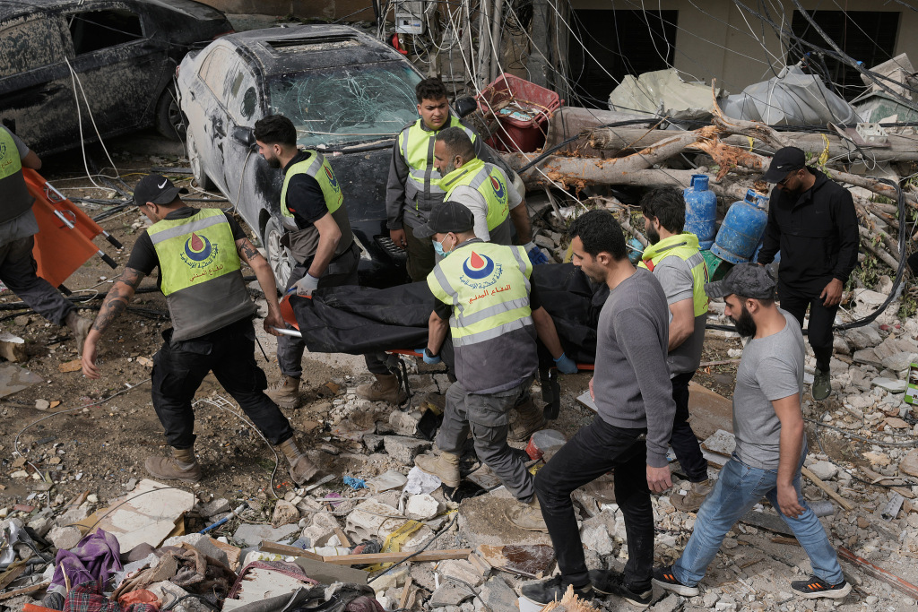 当地时间2026年4月18日，黎巴嫩南部提尔市，救援人员从以色列空袭摧毁的建筑废墟下搬运遇难者遗体。视觉中国 图
