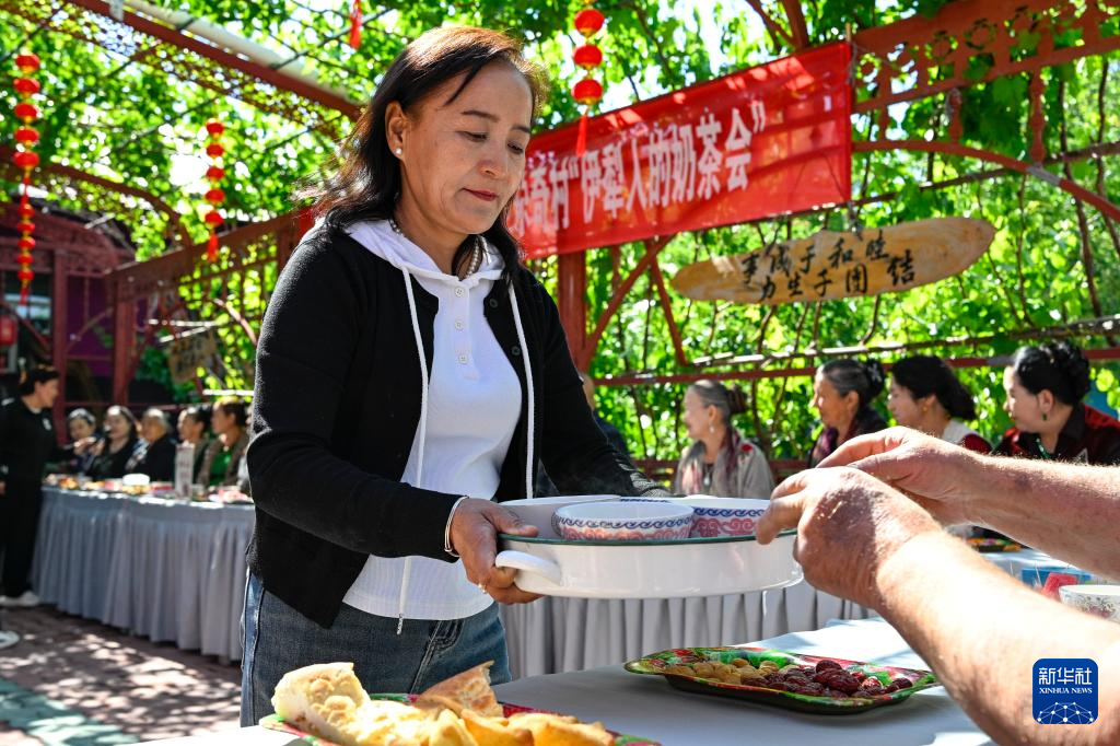在新疆伊宁县喀拉亚尕奇乡喀拉亚尕奇村“伊犁人的奶茶会”现场，工作人员为村民端上奶茶（5月14日摄）。
