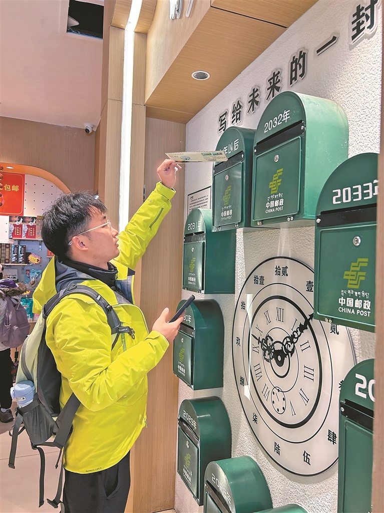 图为游客李先生将写给十年后自己的信投进“时光邮筒”。记者 晓勇 摄