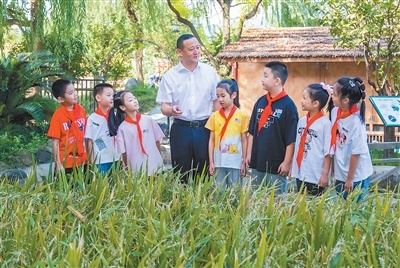 章振乐和学生在富春七小“开心农场”察看农作物长势。