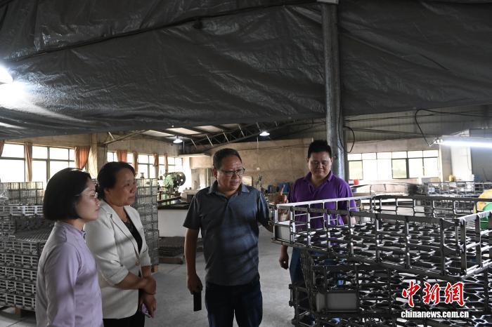 图为庄文祈(右二)和庄钛德(右一)向来客介绍工厂生产情况。中新网记者 蒋雪林 摄