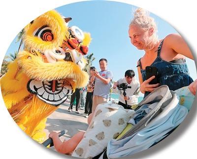 图为近日,在海南三亚,南狮和外国游客零距离互动。