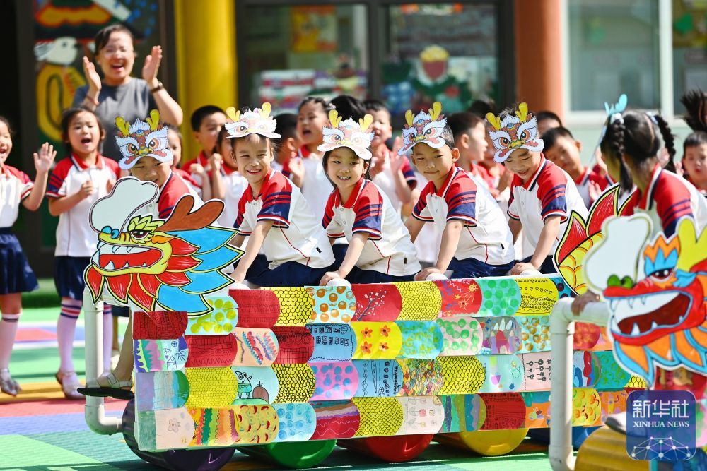 ↑ 6月17日,山东省滕州市北辛街道中心幼儿园举行“品民俗 迎端午”活动,小朋友们在参加“旱地龙舟”趣味比赛。新华社发(李志军摄)