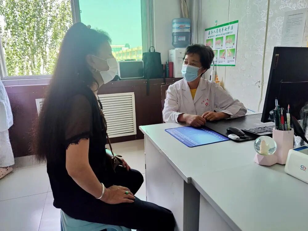 2022年8月1日,准格尔旗妇幼保健院,段仙芝(右)正在问诊一名前来做宫颈癌筛查的女性。