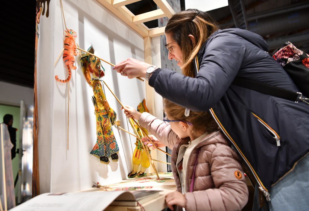 2023年4月25日，在意大利佛罗伦萨举办的国际手工艺展览会上，参观者体验中国皮影文化。