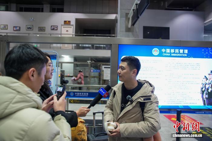 图为中国旅客朱良东从友谊关口岸入境后接受中新网记者采访。陈冠言 摄