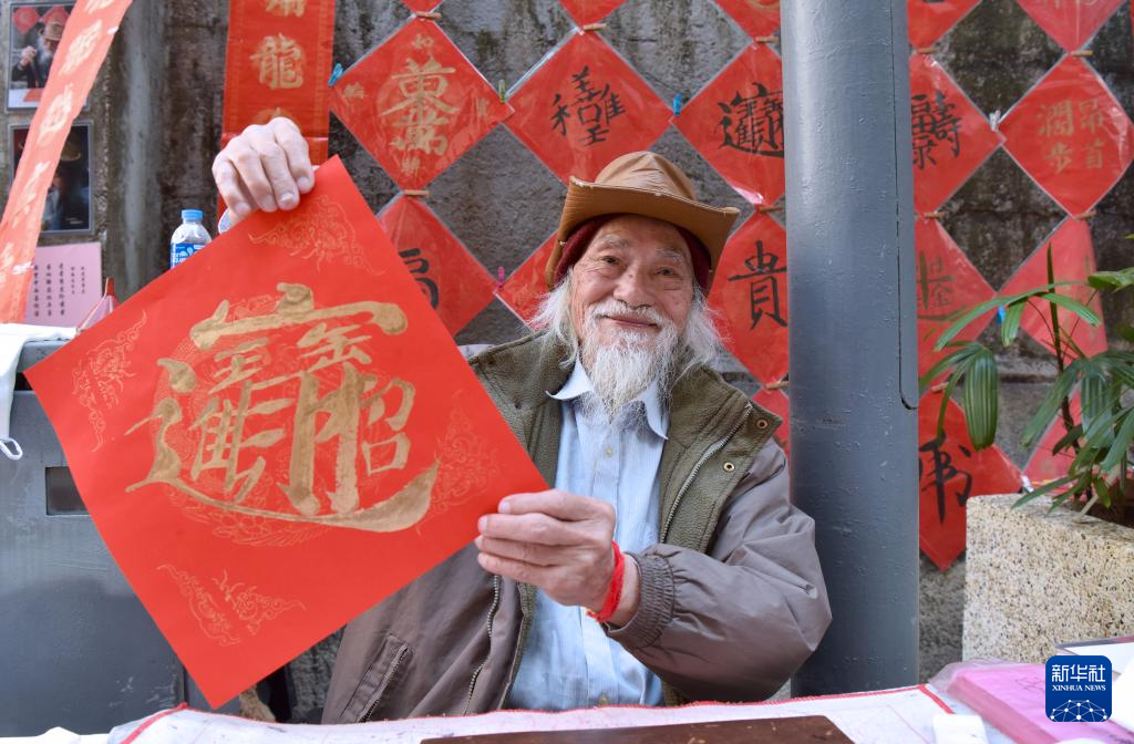 2月13日,在香港楼梯街,郭腾龙展示自创的合体字挥春。新华社记者 陈铎 摄