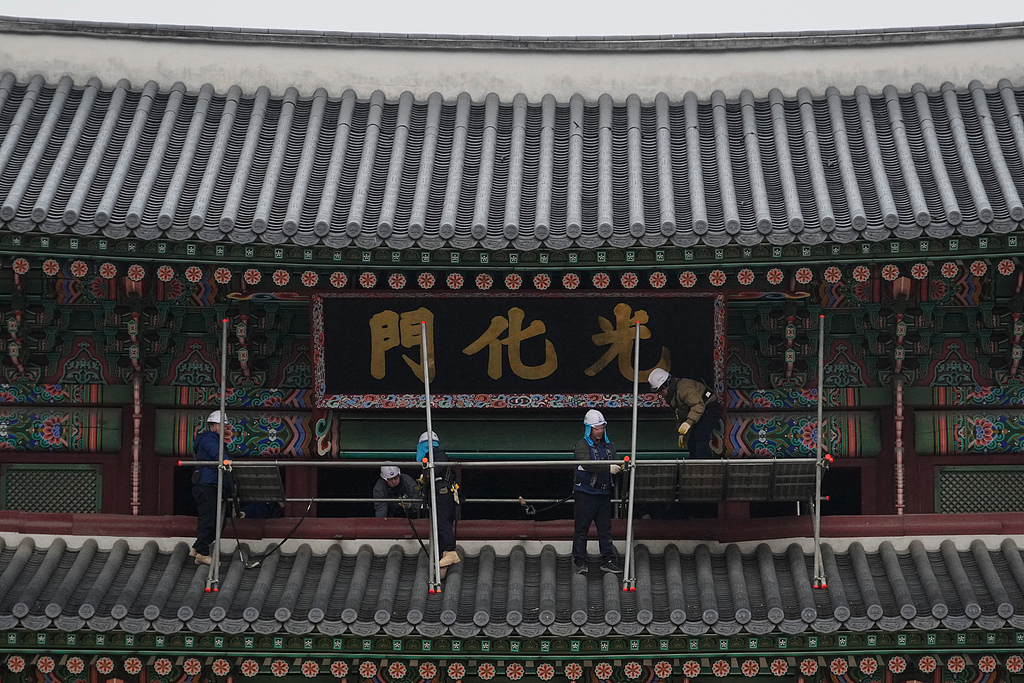 2025年12月16日,韩国首尔,工人们在景福宫正门光化门搭建脚手架并检查招牌。(视觉中国)
