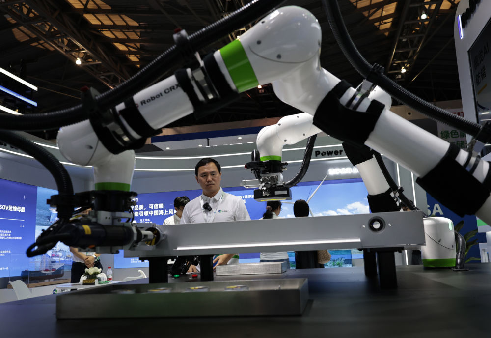 2025年6月11日，在上海举行的第十一届中国（上海）国际技术进出口交易会上，工作人员观看进行作业演示的电池包装配及插线检测协作机器人。新华社记者 方喆 摄