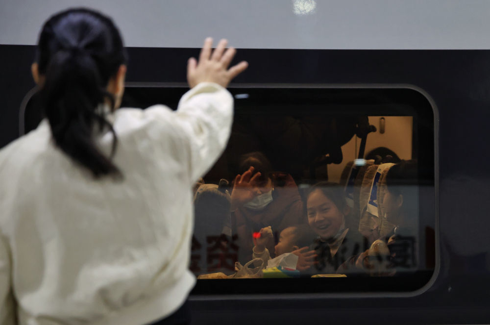 2026年2月2日，在深圳北站，旅客与送站的亲人挥手道别。新华社记者 毛思倩 摄