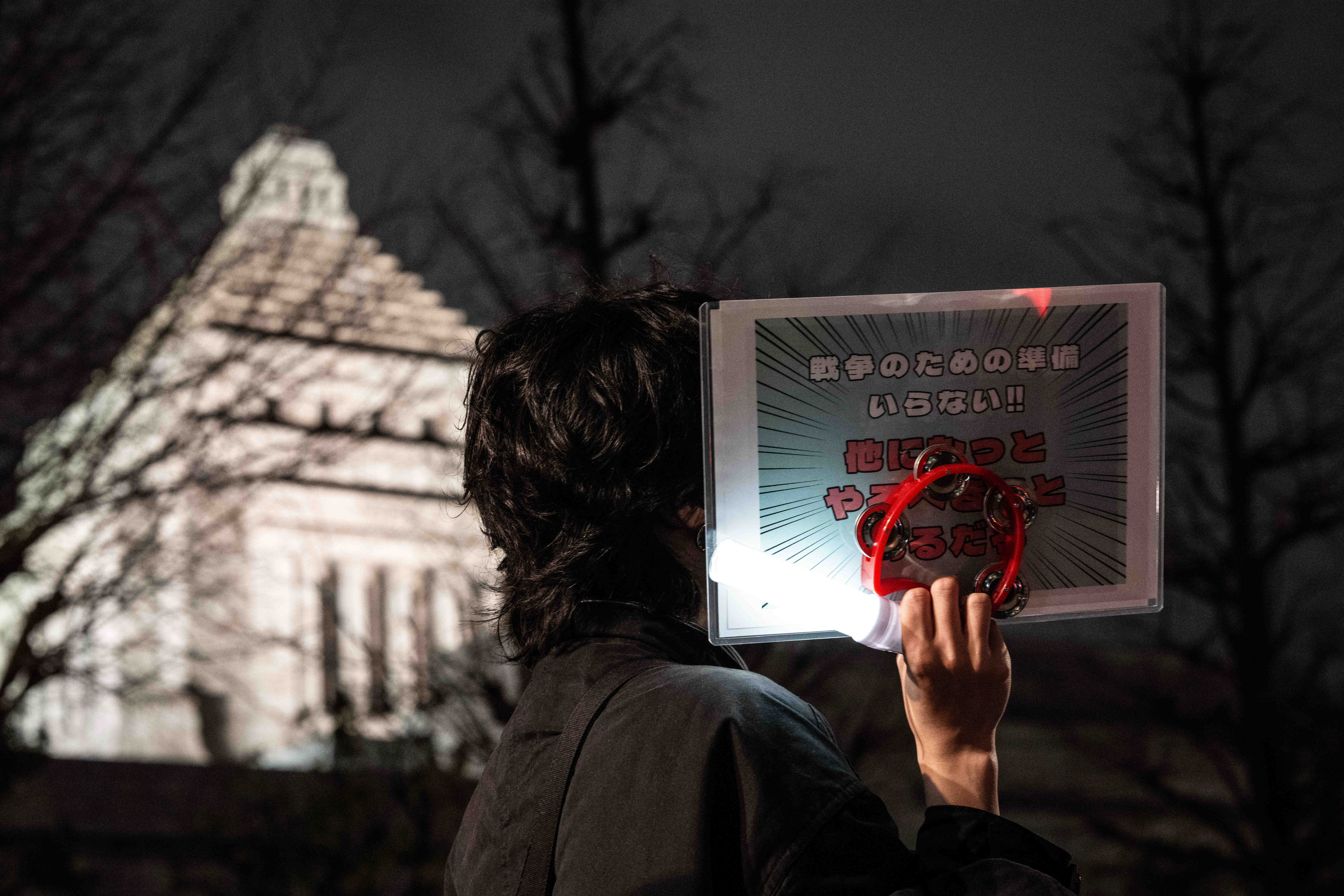 2月24日，在日本东京的众议院第二议员会馆前，一名抗议者手持“不要战争准备”的标语。新华社记者贾浩成摄