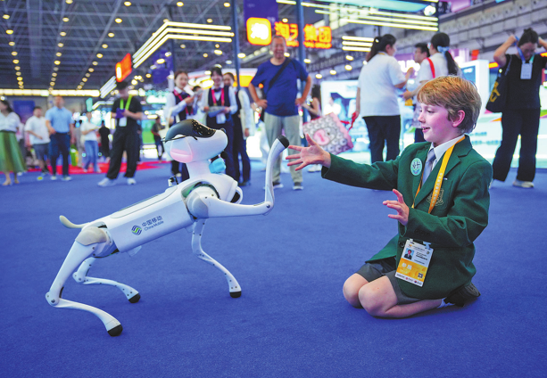 一位外国小朋友正在与机器狗互动。（图片：中国日报）