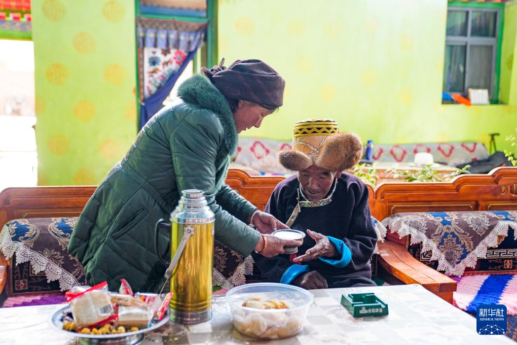 白玛扎西（右）在家中喝酥油茶（3月26日摄）。