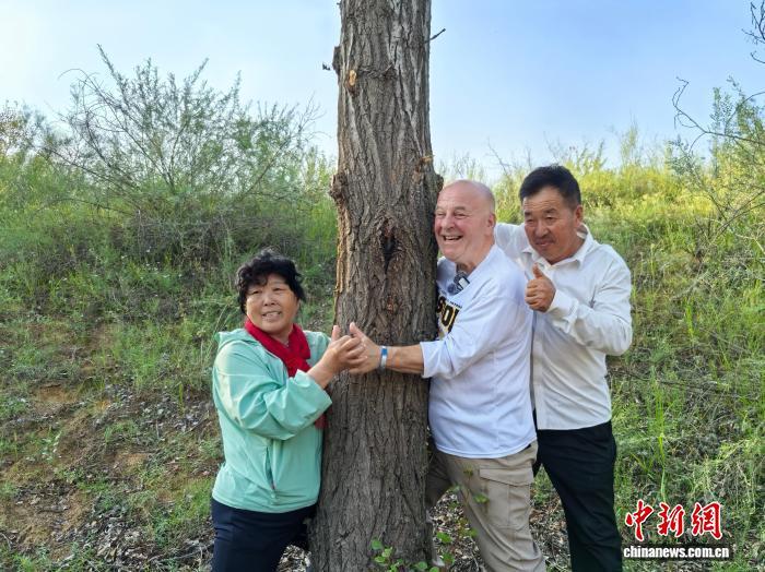8月24日，内蒙古鄂尔多斯市乌审旗，中国“治沙劳模”殷玉珍夫妇和美国友人“赛考斯”(右二)与26年前种下的树合影。中新社记者 曾玥 摄