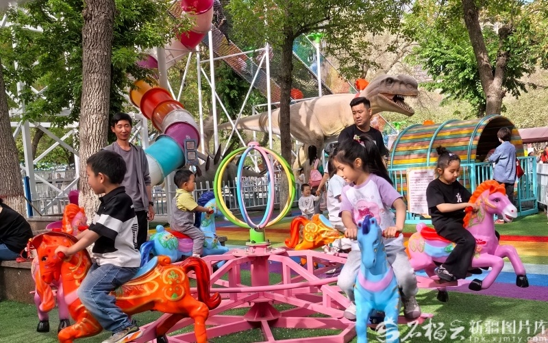 5月2日，在乌鲁木齐市人民公园一处无动力乐园，不少家长在陪孩子一起游玩。石榴云/新疆日报记者 黑宏伟摄