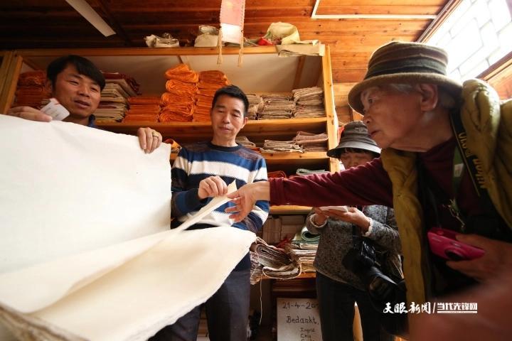 贵州省丹寨县南皋乡石桥村手工皮纸展示馆,王兴武(左二)在向日本游客介绍新式白皮纸的质量。.JPG