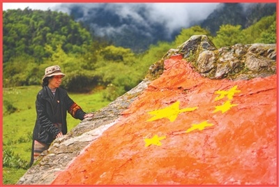 西藏山南市隆子县玉麦乡村民卓嘎规矩了一天的巡边,凝望着由村民们绘图的国旗石。 本报记者 徐驭尧摄