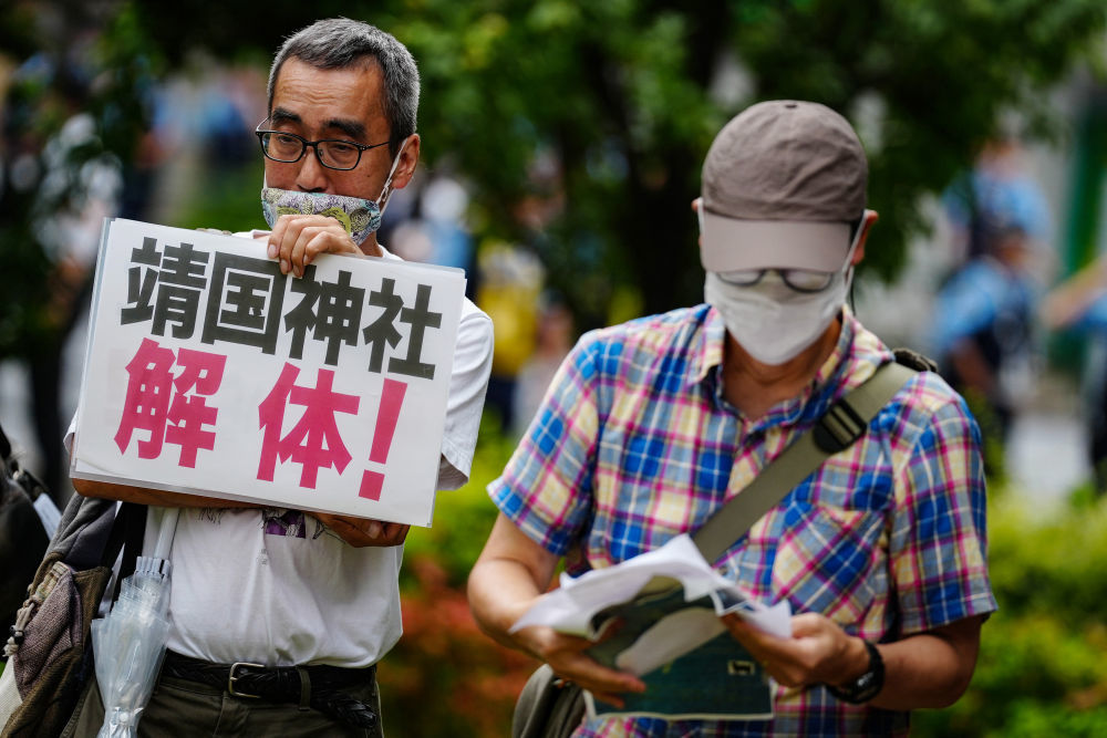 8月15日，在日本东京的淡路公园内，日本民众手持标语参加集会。新华社记者贾浩成摄
