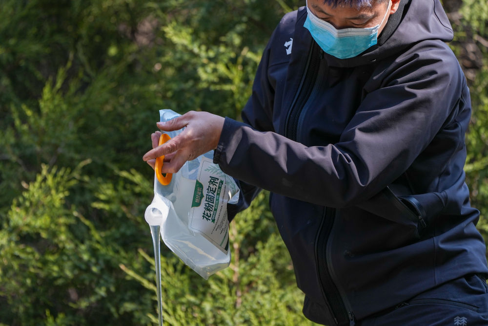 3月15日，在北京地坛公园，工作人员在向洒水车内添加花粉固定剂。新华社记者 鞠焕宗 摄