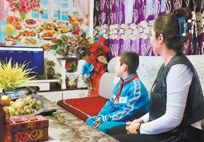 艾孜热提罕&middot;木沙和儿子在新家一起看电视。　　本报记者 尚嵘峥摄