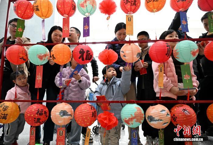 13日，在福州举行的“话百家姓、过中国年”主题文化活动中，旅客正在体验猜灯谜活动。　中新网记者 吕明 摄