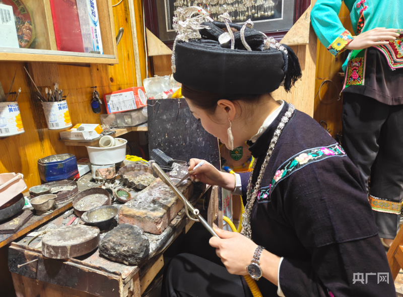 蒙梅香端坐案前，专注地进行银饰精密焊接（央广网记者 栾小琳 摄）