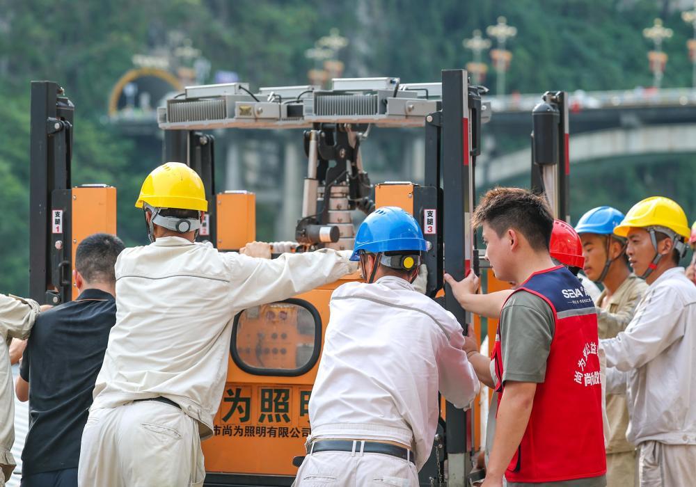 7月17日,志愿者在重庆彭水县山体崩塌救援现场协助搬运电力照明设备。