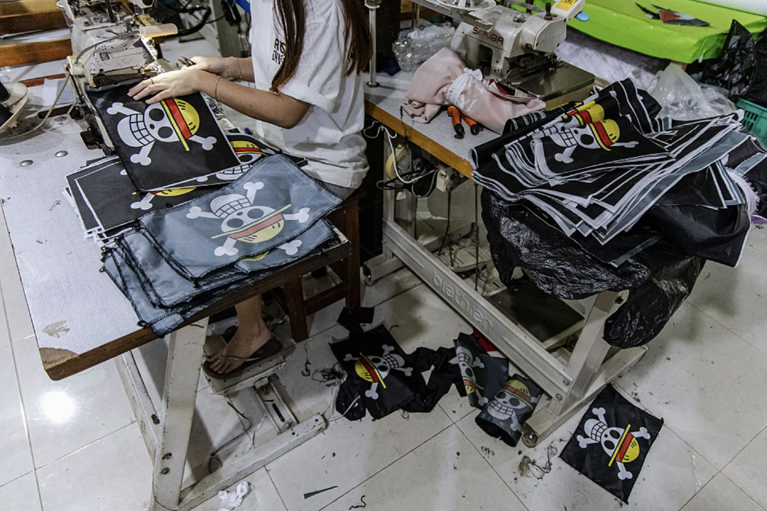 2025年8月10日，在印尼爪哇省卡兰加尼亚尔的一家服装作坊里，工人正在制作草帽团旗帜