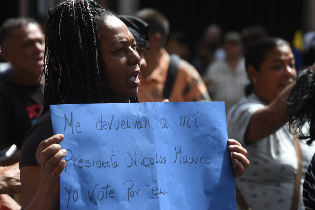 1月3日,一名抗议者手举标语在委内瑞拉首都加拉加斯参加抗议活动。