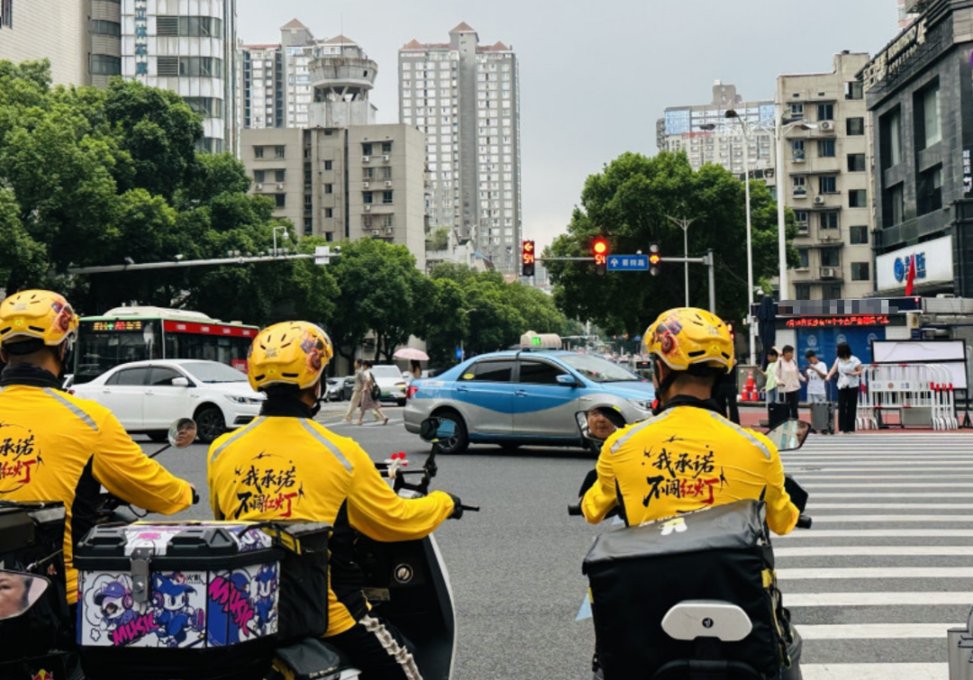美团骑手在路口等候红灯。图源:长沙晚报