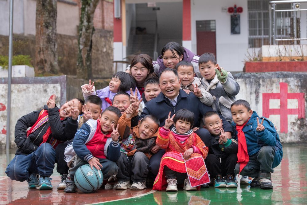 农加贵和学生们在落松地小学操场上合影。新华社记者 彭奕凯 摄