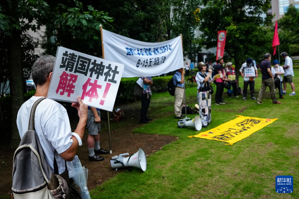 8月15日，在日本东京的淡路公园内，日本民众手持标语参加集会。新华社记者 贾浩成 摄