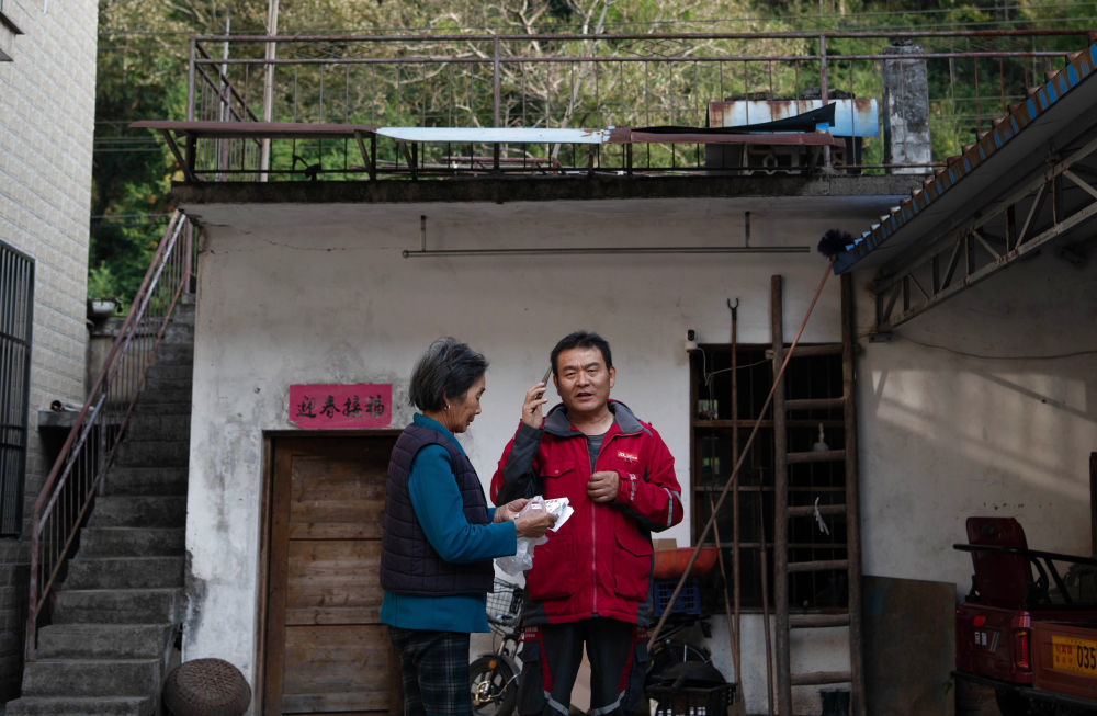 2025年10月27日，在安徽省石台县莲花村，快递员檀世旺帮助在外地务工的村民给家中老人送药。新华社记者 张端 摄
