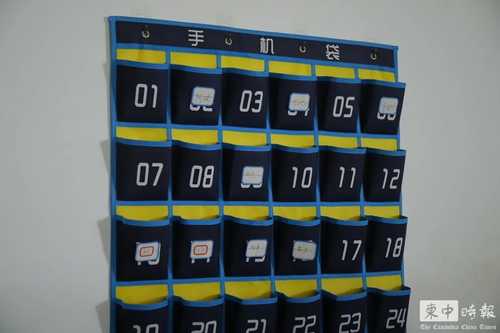 办公区域墙上设置编号“手机袋”,部分位置贴有中文姓名标签。(图:柬中时报)