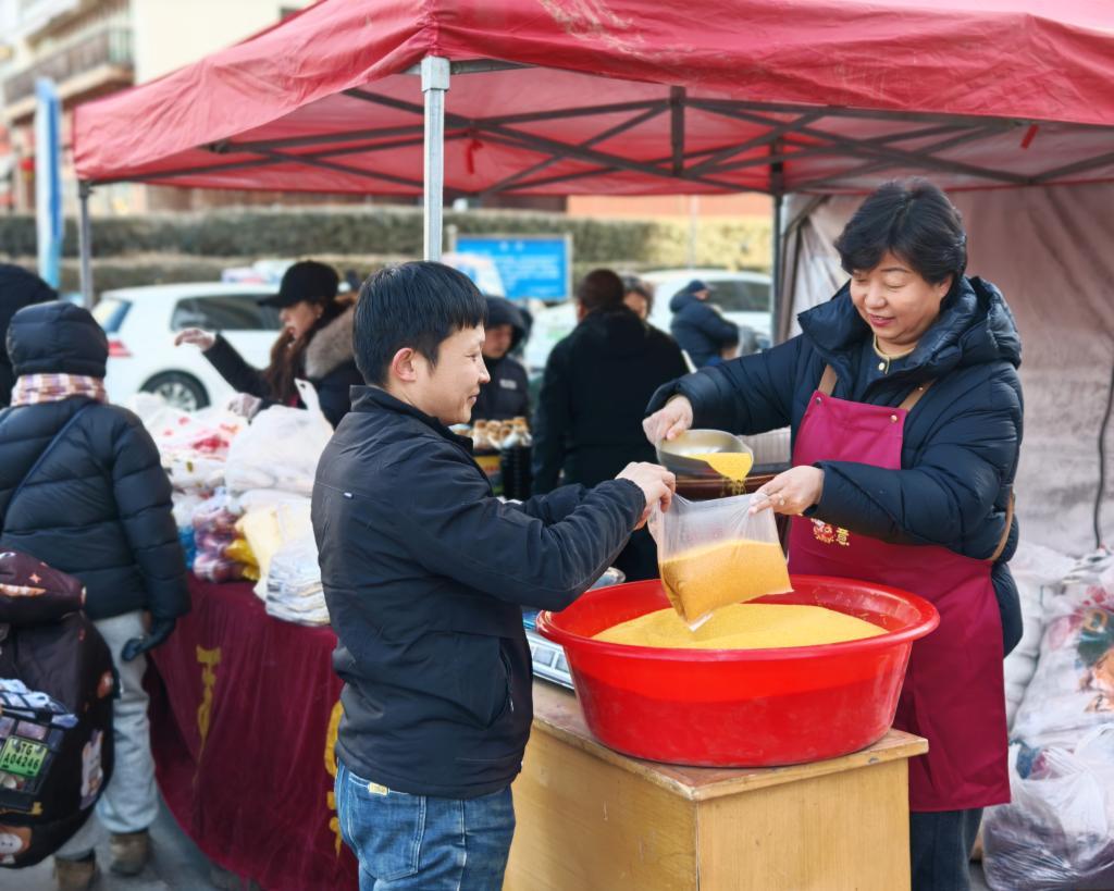 2月11日，尤变清（右）在太原市区销售点推销南留南村特色农产品。新华社发（田佳伟摄）