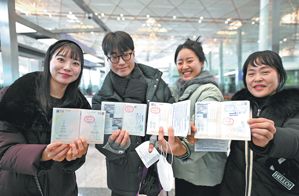 韩国游客在北京首都国际机场展示护照上的入境印章。（图片来源：新华社）