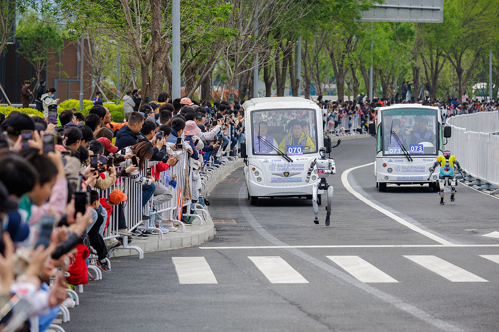 2026年4月19日,北京亦庄人形机器人半程马拉松赛场上,两台机器人“你追我赶”。视觉中国 图