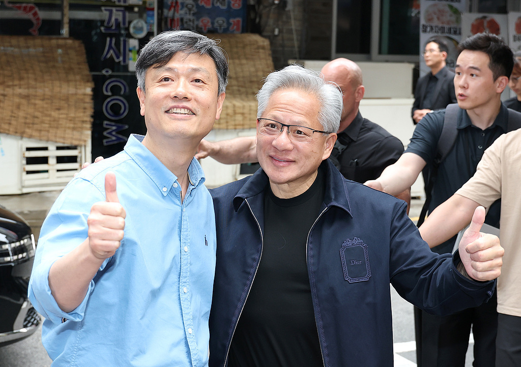 当地时间2026年6月7日，韩国首尔，英伟达公司首席执行官黄仁勋（右）与KRAFTON执行董事张炳圭在一家网吧前合影。视觉中国 图