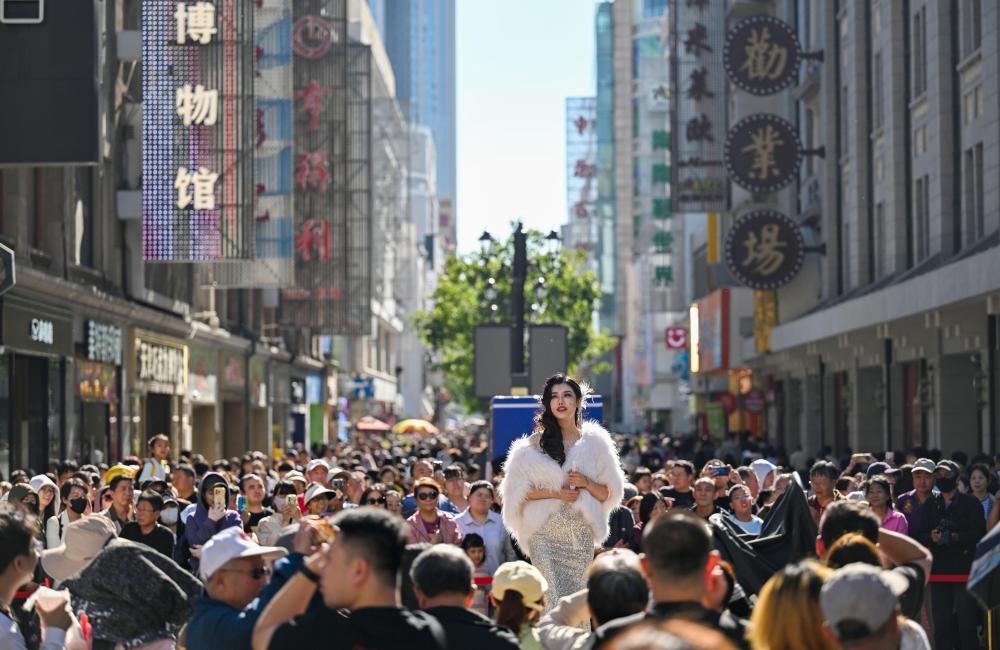 10月6日,游客在天津金街观看话剧《日出》片段表演。