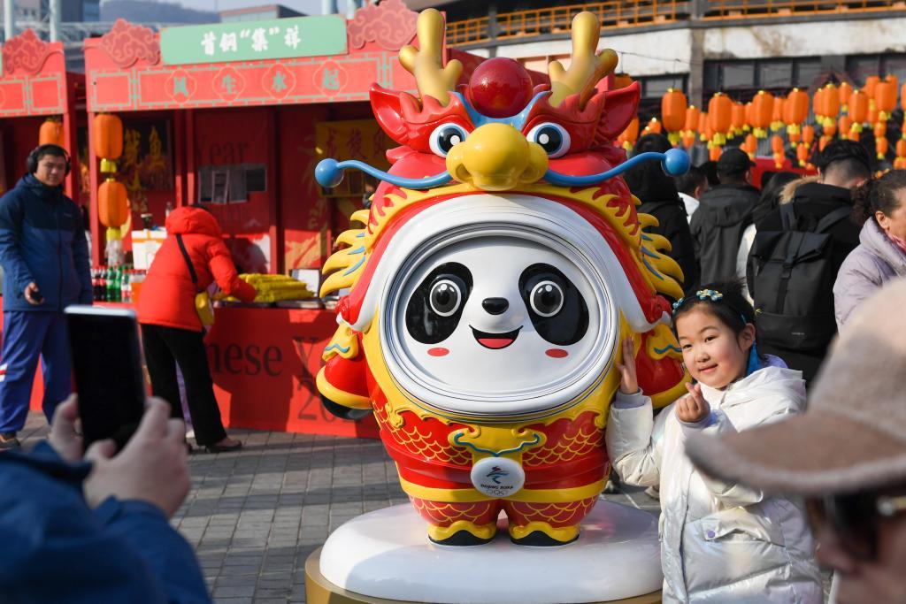 2024年2月13日,小朋友在北京首钢园的龙年古风游园会与“龙墩墩”合影。新华社记者 鞠焕宗 摄