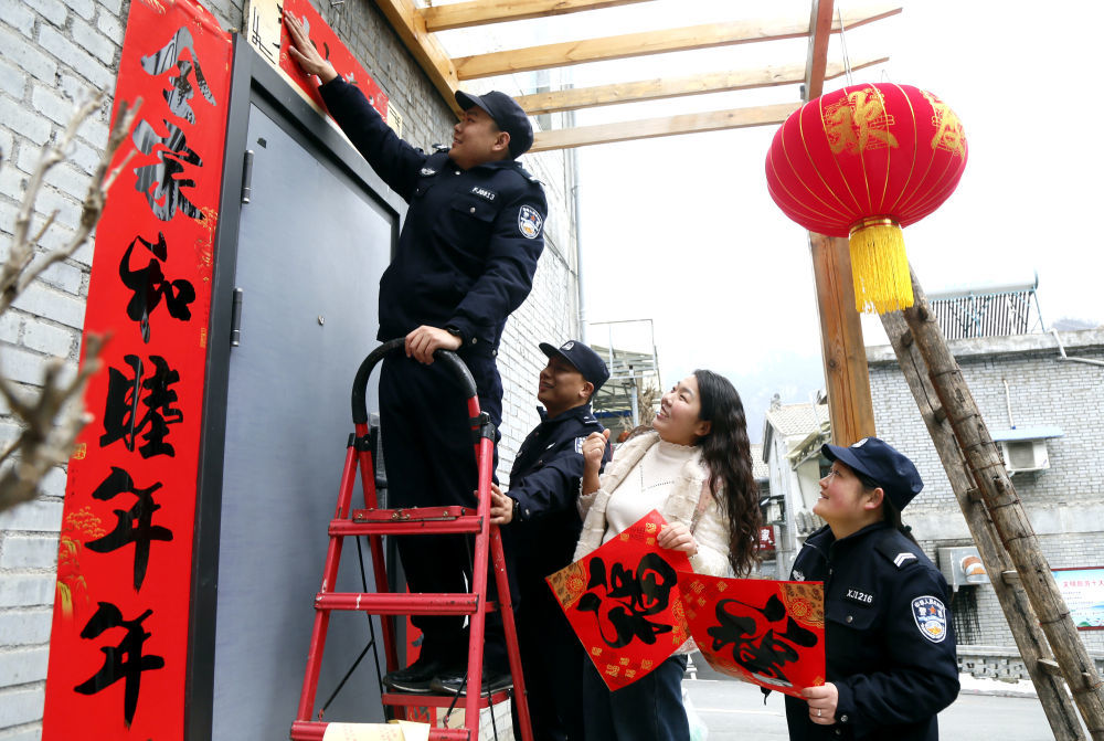 ↑ 2月15日，河南省洛阳市汝阳县付店派出所民辅警给居民家贴春联挂灯笼，送去新春祝福。新华社发（康红军摄）