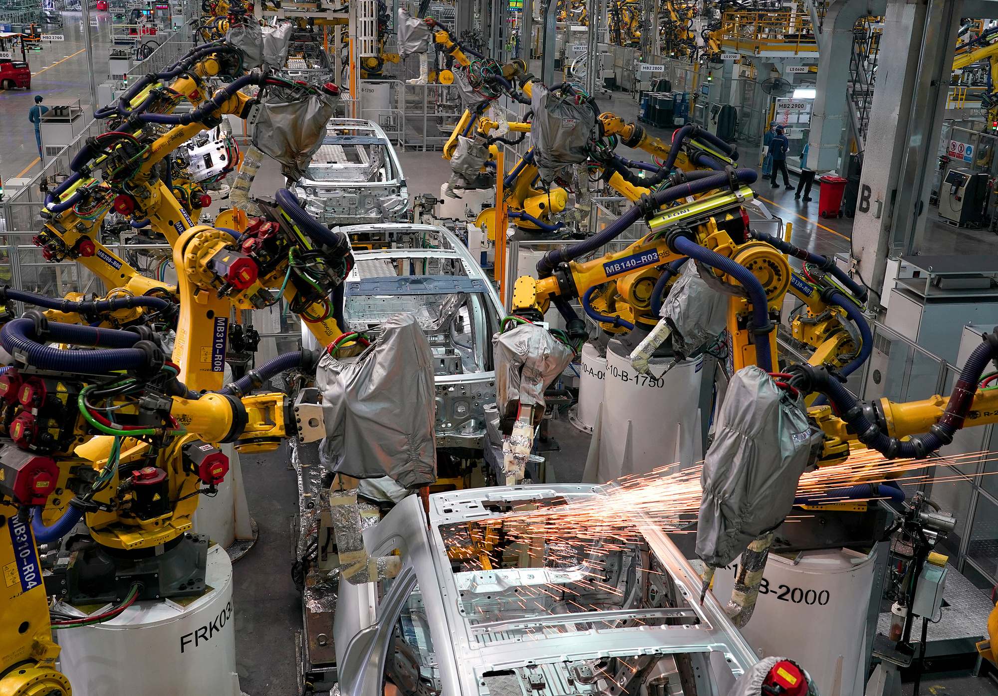 重庆国际物流枢纽园区的超级工厂内，工业机器人进行焊接作业