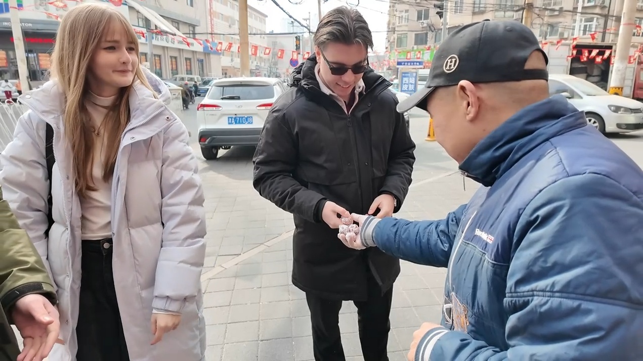 一名店铺商户让匈牙利友人品尝糖墩儿