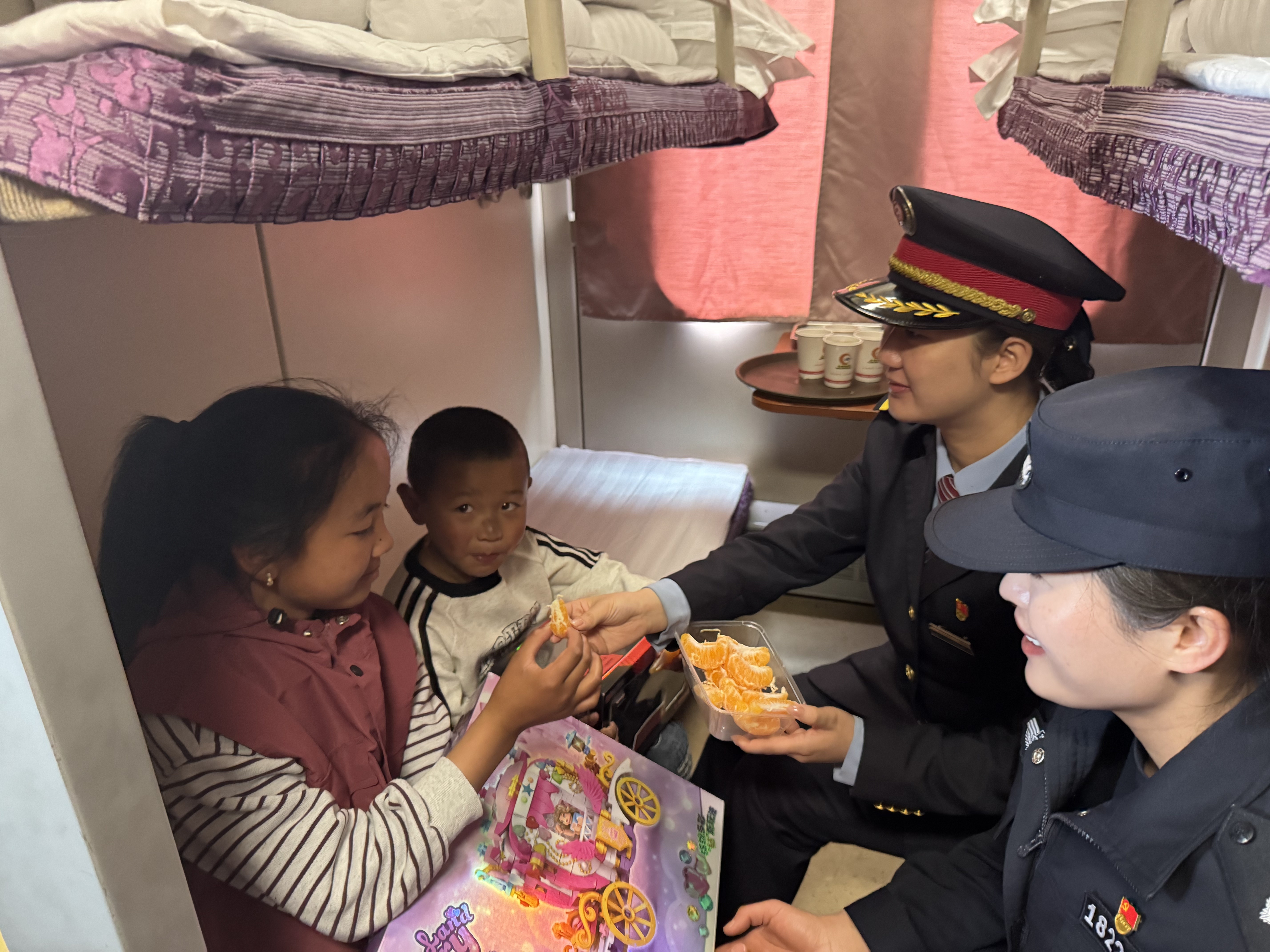 图为2026年5月26日，Z166拉萨开往上海的列车上，列车员和铁路警察给小朋友送水果。记者 康洁白姆 摄