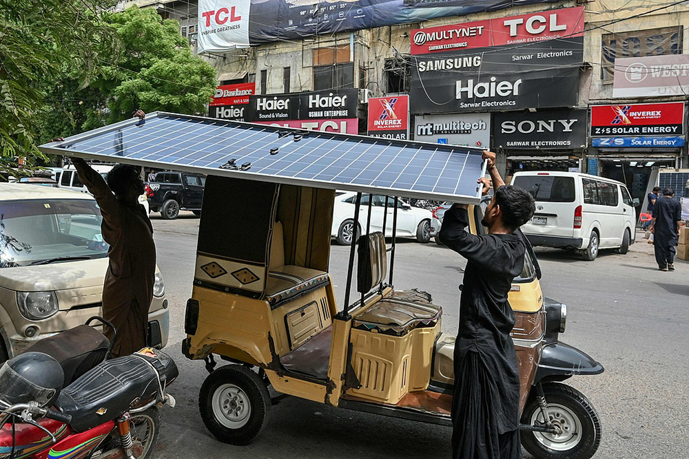 2025年6月23日,巴基斯坦卡拉奇,工人们将太阳能电池板装载到一辆自动人力车上。视觉中国 资料图