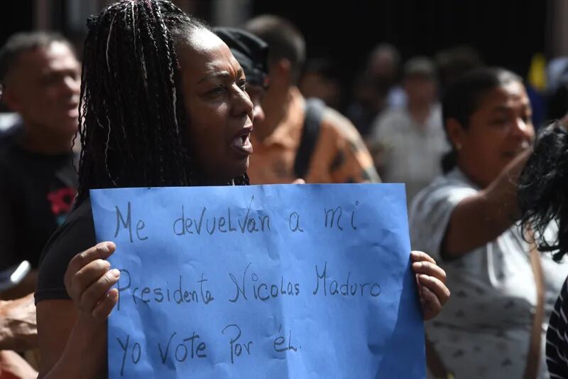 1月3日,一名抗议者手举标语在委内瑞拉首都加拉加斯参加抗议活动 图:新华社