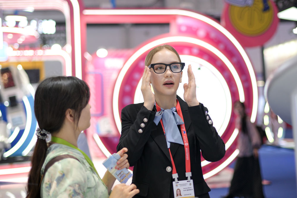 ↑ 4月14日，在第六届消博会科技消费展区，科大讯飞工作人员（右）为观众调试一款具有镜片实时投射翻译等功能的AI眼镜产品。新华社记者 辛悦卫 摄