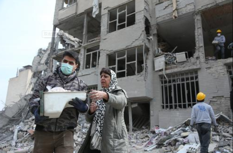 图为在伊朗德黑兰,市民站在建筑废墟前。